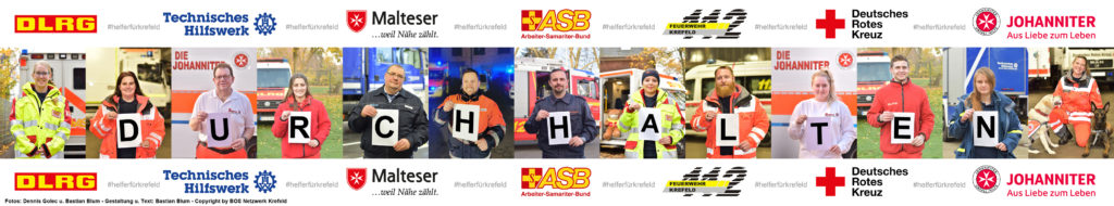Verschiedene Helfer der Krefelder Hilfsorganisationen und Freiwilligen Feuerwehren bilden mit Zetteln den Schriftzug "Durchhalten"